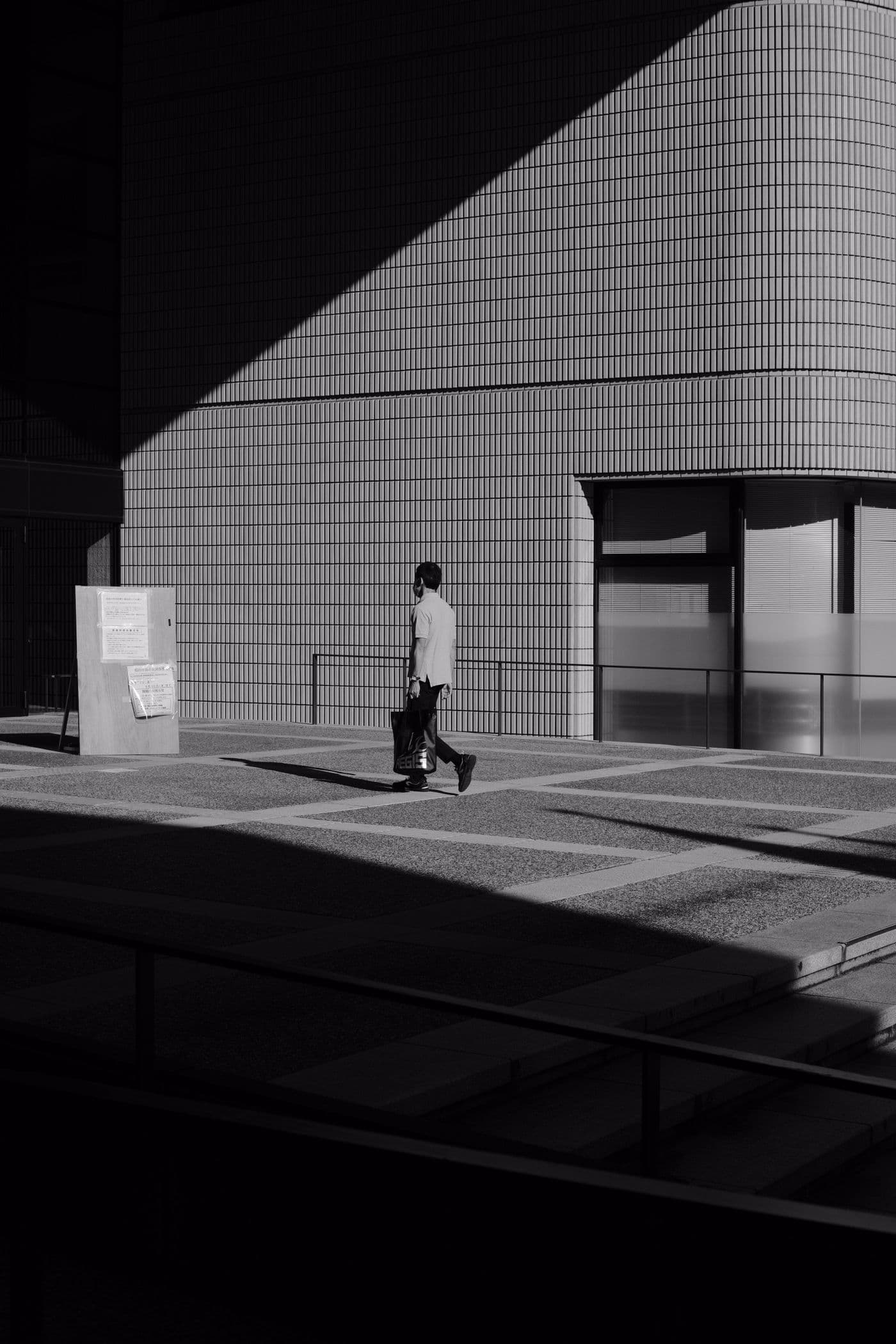 A person walking through the shadows of a modern city